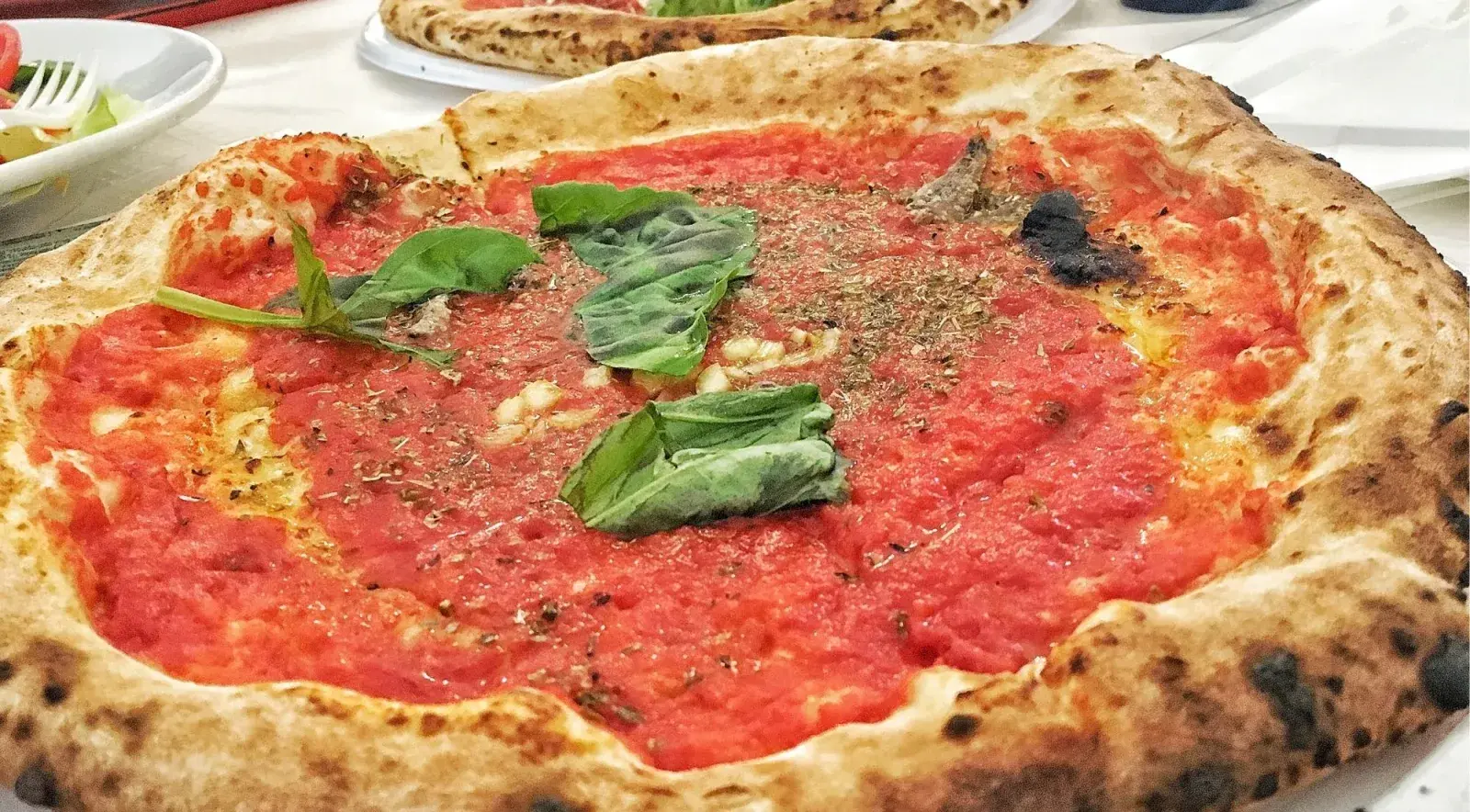 Classic Neapolitan pizza marinara with San Marzano tomatoes, basil and the characteristic leopard-spot charred crust